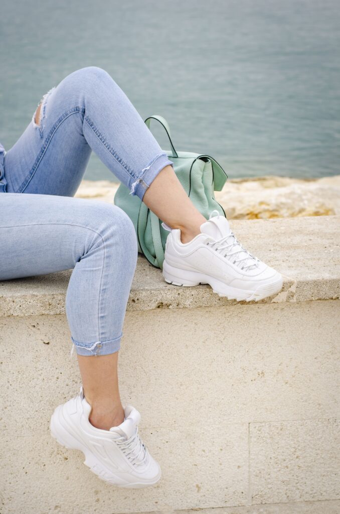 Fashionable urban outfit photo: Female legs in blue jeans and white sneakers, showcasing a casual everyday clothing style