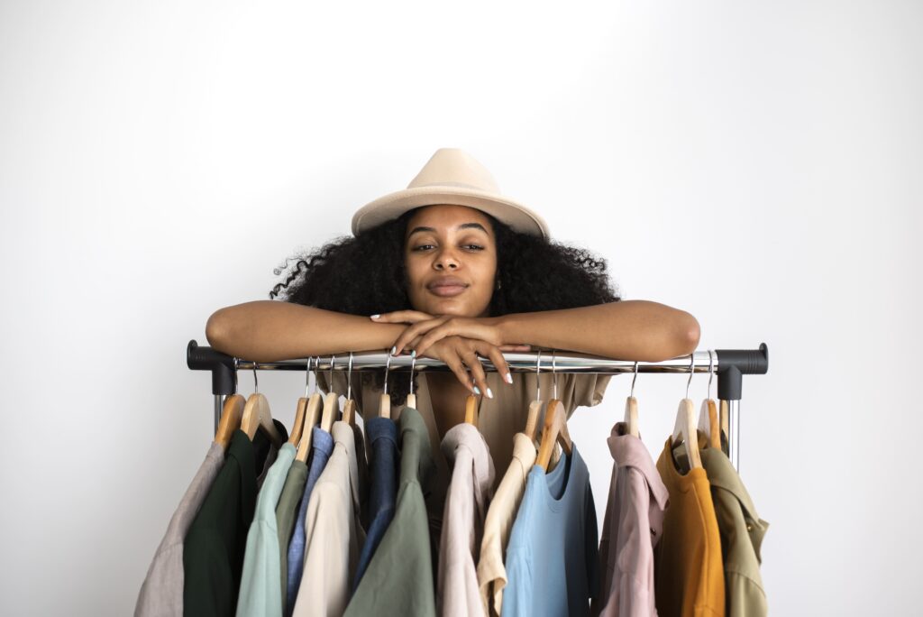 Woman building her capsule wardrobe, seen from the front wearing a hat.