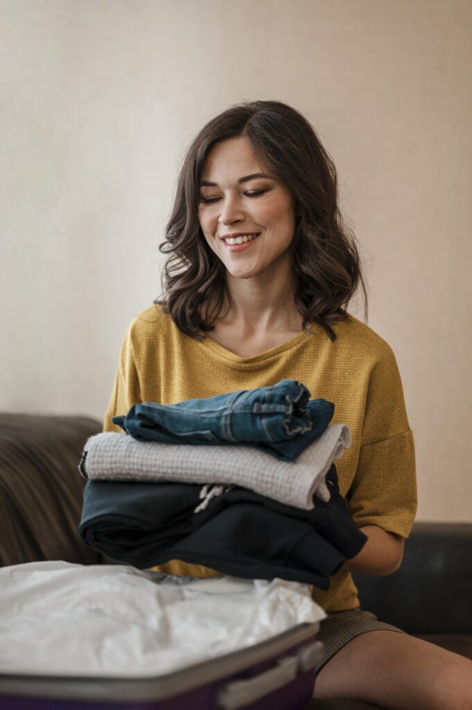 A medium shot of a woman with neatly folded clothes