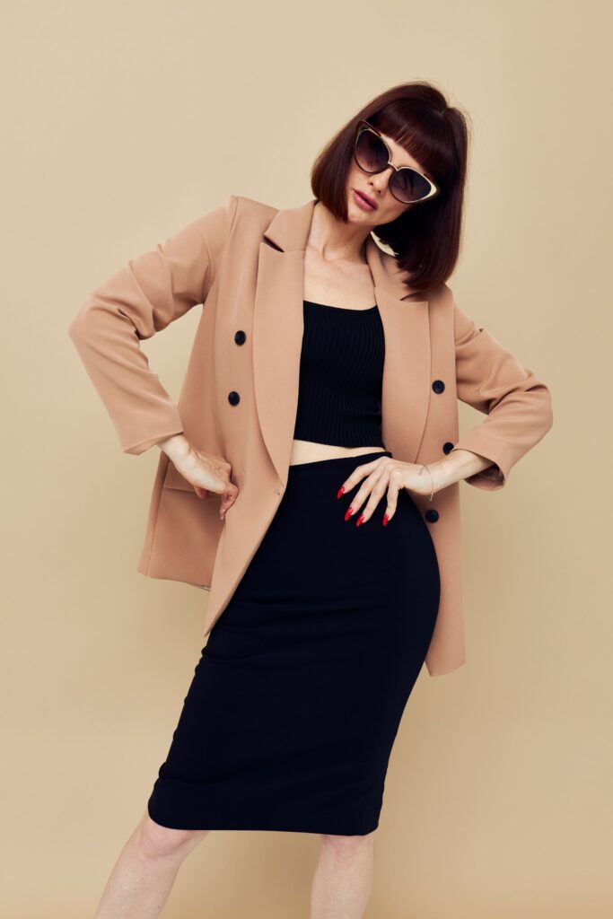 A woman wearing sunglasses and a short hairstyle, dressed in a suit and gesturing with her hands, representing a confident and unchanged lifestyle.