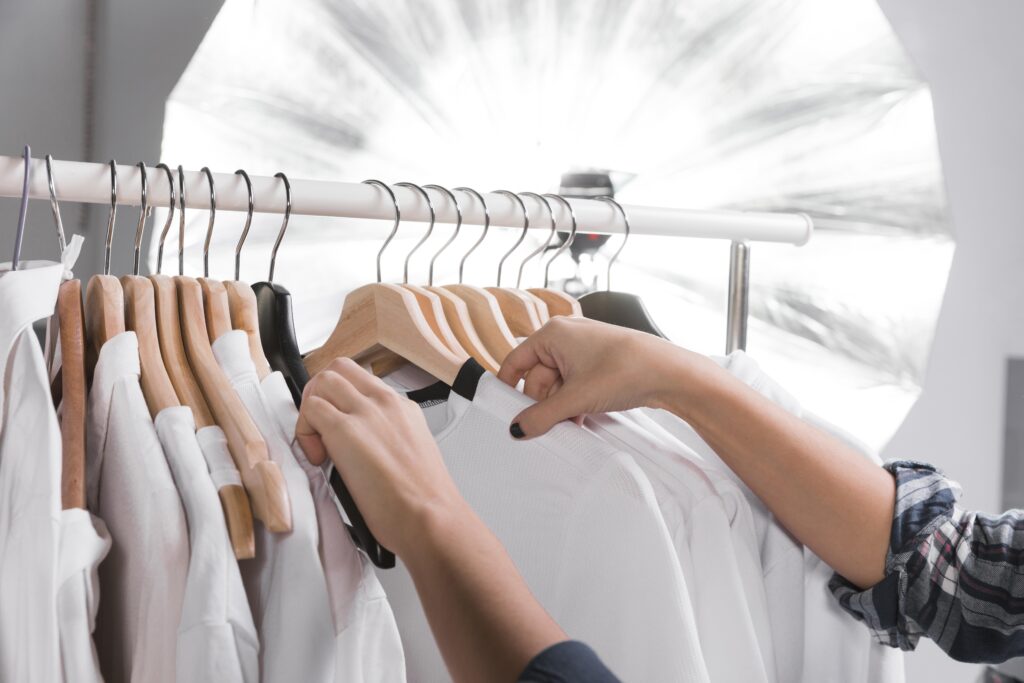 Woman selecting outfits for a photoshoot on a hanger in an image