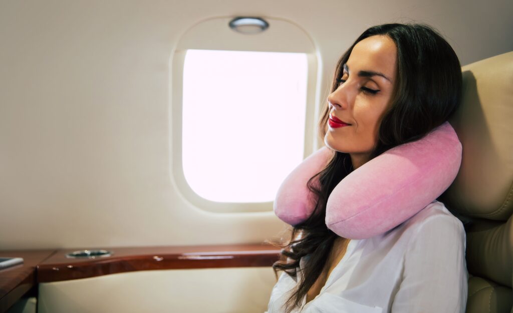 A close-up photograph of a lovely lady wearing a white blouse, peacefully taking a nap in her window seat on a business class aircraft. Relevant tags include airplane seat, plane seat, flight, travel plane, flying plane, airline, and 29+.