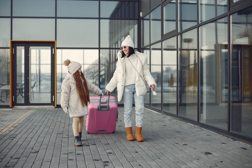 Mother and daughter with luggage going from airport terminal