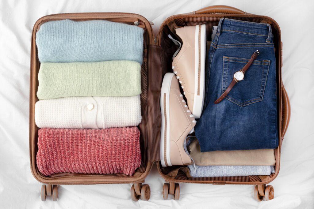An image of an open luggage with neatly folded clothes and shoes.