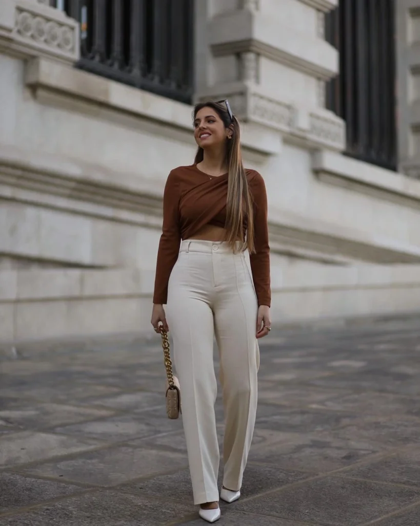 Woman wearing neutral brown crop long sleeve short and a cream wide leg pants walking down the road in white heels