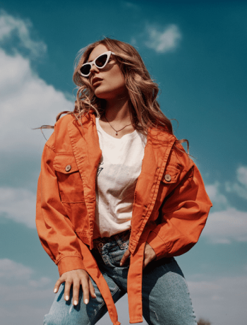 Elegant fashion portrait of a sophisticated woman with a keen fashion sense, wearing fashionable jackets and jeans, posing outdoors in a chic style.