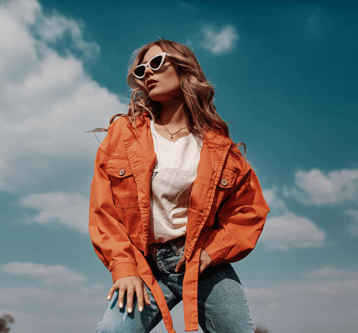 Elegant fashion portrait of a sophisticated woman with a keen fashion sense, wearing fashionable jackets and jeans, posing outdoors in a chic style.