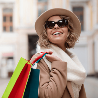 Medium shot of a cheerful woman carrying shopping bags, showcasing fashion on a budget