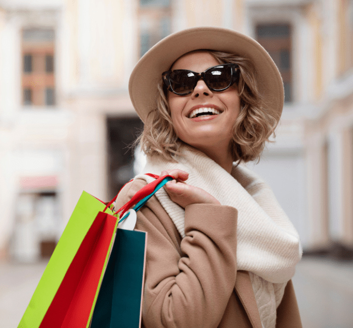 Medium shot of a cheerful woman carrying shopping bags, showcasing fashion on a budget