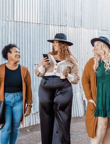 Group of women of different sizes, showcasing how to dress for your body type, wearing stylish bikinis and standing together against a brown background. Diverse women in swimwear looking at camera and smiling.