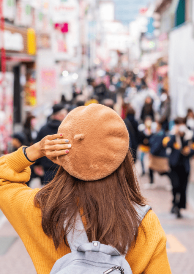 Young woman traveler in versatile clothing for travel, exploring Harajuku's Takeshita Street, the center of teenage fashion and cosplay culture in Tokyo