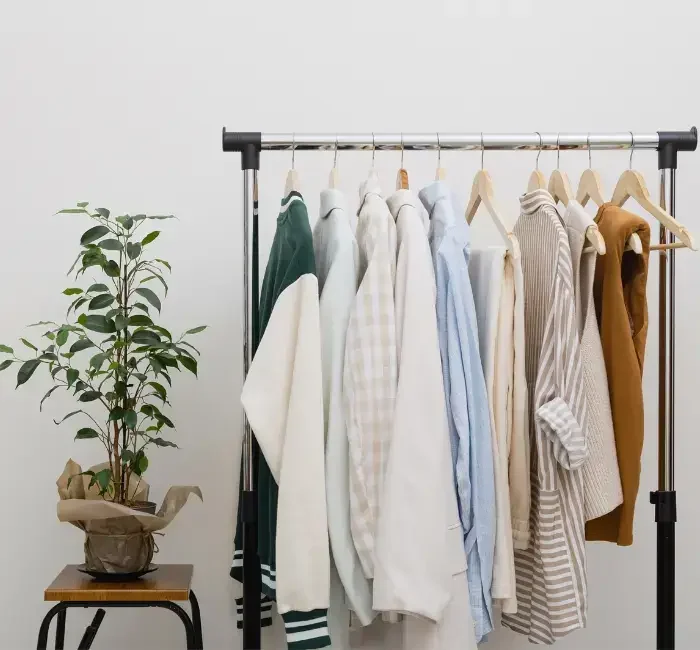 A minimalist wardrobe with neatly hung neutral-toned clothing on a rack, demonstrating how to upgrade your wardrobe with timeless pieces and sustainable fashion choices.