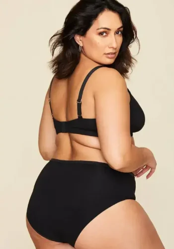 A woman with a confident expression modeling black plus-size lingerie, showcasing body positivity and inclusive fashion.