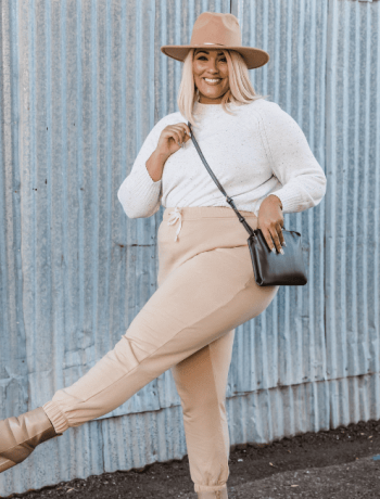 Stylish Plus Size Woman Posing Near Corrugated Metal Wall with Her Plus Size Capsule Wardrobe