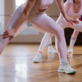 Women engage in a stretching routine that perfectly illustrates the effectiveness of a gym capsule wardrobe for women. Their attire highlights both the style and functionality necessary for diverse workouts, emphasizing the importance of versatile, fashionable, and comfortable fitness clothing.