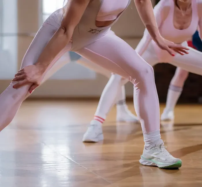 Women engage in a stretching routine that perfectly illustrates the effectiveness of a gym capsule wardrobe for women. Their attire highlights both the style and functionality necessary for diverse workouts, emphasizing the importance of versatile, fashionable, and comfortable fitness clothing.