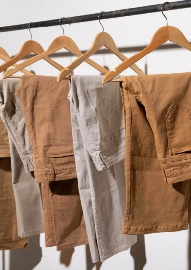 An assortment of beige-toned pants neatly hung on a hanger, showcasing a variety of styles perfect for a minimalist wardrobe.