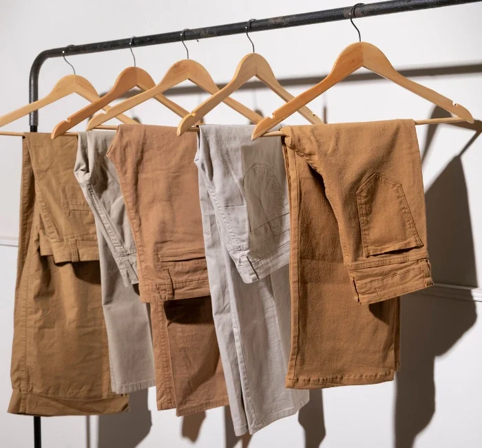 An assortment of beige-toned pants neatly hung on a hanger, showcasing a variety of styles perfect for a minimalist wardrobe.