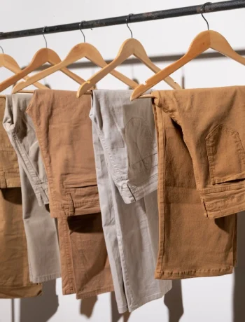 An assortment of beige-toned pants neatly hung on a hanger, showcasing a variety of styles perfect for a minimalist wardrobe.