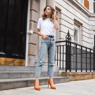 Woman wearing a white shirt , denim jeans with red high heels showcasing her smart casual look