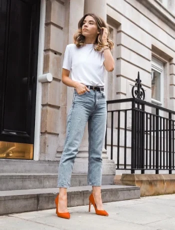 Woman wearing a white shirt , denim jeans with red high heels showcasing her smart casual look