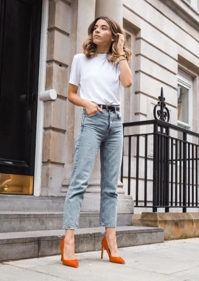 Woman wearing a white shirt , denim jeans with red high heels showcasing her smart casual look