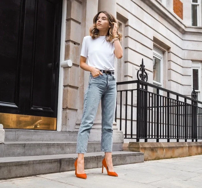 Woman wearing a white shirt , denim jeans with red high heels showcasing her smart casual look