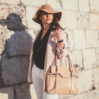 Plus-size model showcasing spring casual fashion with a neutral blazer, hat, and handbag, walking down the city street, displaying the art of accessorizing elegantly.