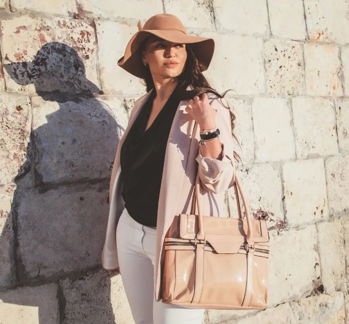 Plus-size model showcasing spring casual fashion with a neutral blazer, hat, and handbag, walking down the city street, displaying the art of accessorizing elegantly.