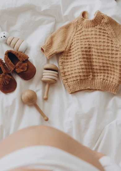 Top view of a pregnant woman's belly bump with stylish brown boho shoes, illustrating a maternity capsule wardrobe