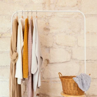 Neutral-toned women's apparel arranged on a clothing rack, demonstrating a minimalist capsule wardrobe concept.