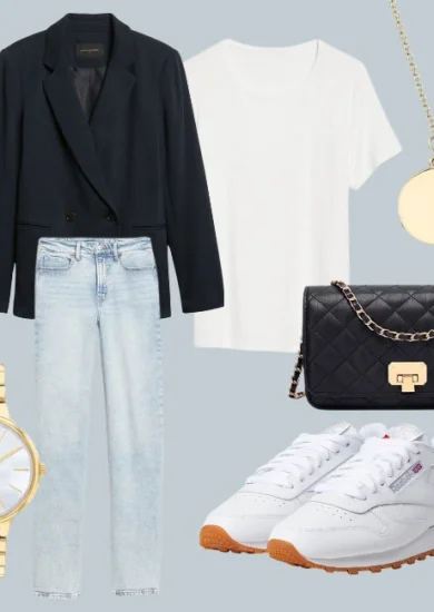 Fall capsule wardrobe 2023: An ensemble from the autumn capsule collection featuring a white shoe, a navy blue blazer, light wash denim jeans, a golden necklace and watch, completed with a black cross-body bag and crisp white shirt.