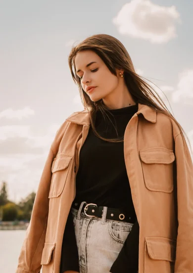 Photo of a caucasian young pretty stylish woman standing near river lake water street on sand pier showcasing Fall Minimalist Fashion