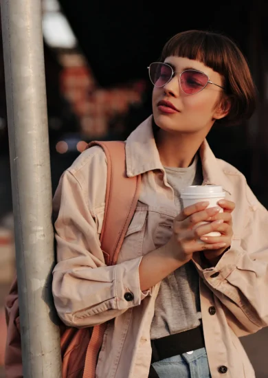 Woman in a Fall to Winter Minimalist Wardrobe, looking stylish in a tight outfit, holding a cup of tea in the city.