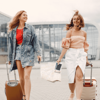 Two beautiful girls standing by the airport, showcasing their skill in traveling light