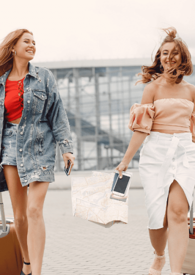 Two beautiful girls standing by the airport, showcasing their skill in traveling light